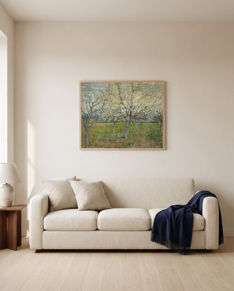 The Pink Orchard by Vincent van Gogh framed in natural oak above a cream sofa in a warm living room