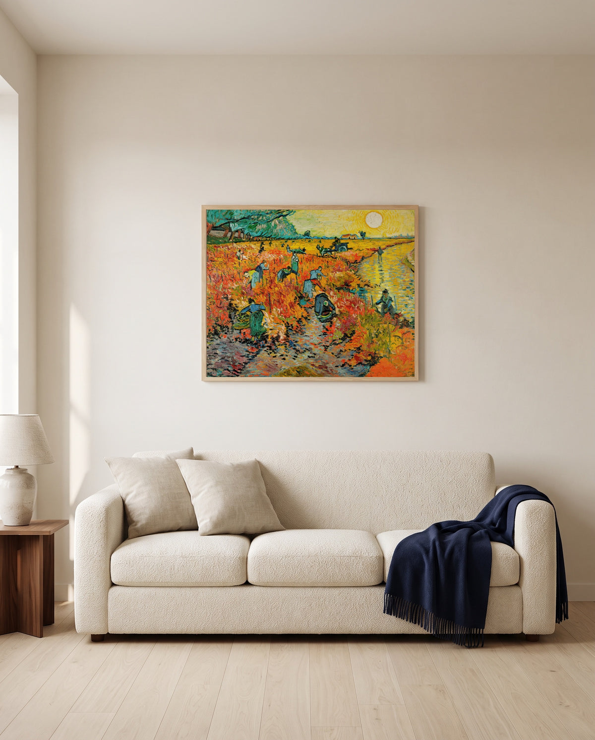 The Red Vineyard by Vincent van Gogh framed in natural oak above a cream sofa in a warm living room