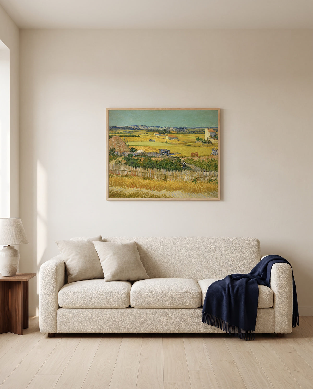 The Harvest by Vincent van Gogh framed in natural oak above a cream sofa in a warm living room