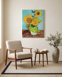Three Sunflowers in a Vase by Vincent van Gogh as a stretched canvas above a linen lounge chair in a reading corner