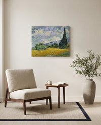 Wheat Field with Cypresses by Vincent van Gogh as a stretched canvas above a linen lounge chair in a reading corner