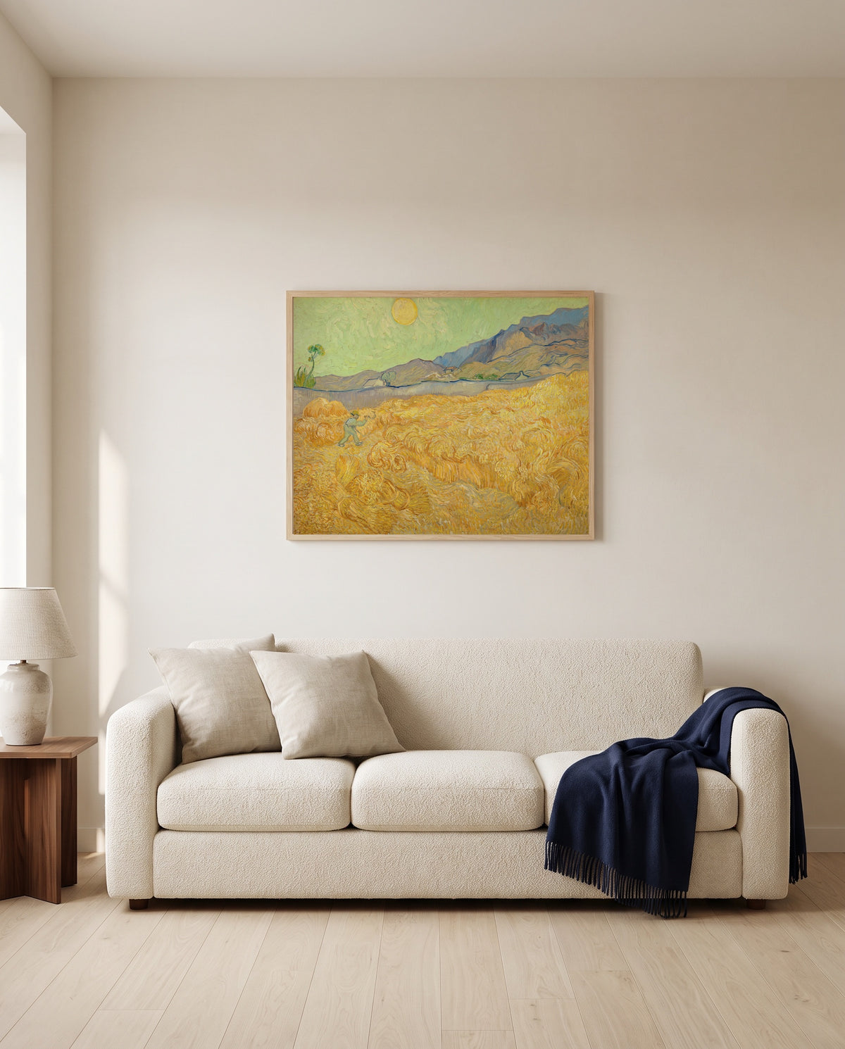 Wheatfield with a Reaper by Vincent van Gogh framed in natural oak above a cream sofa in a warm living room