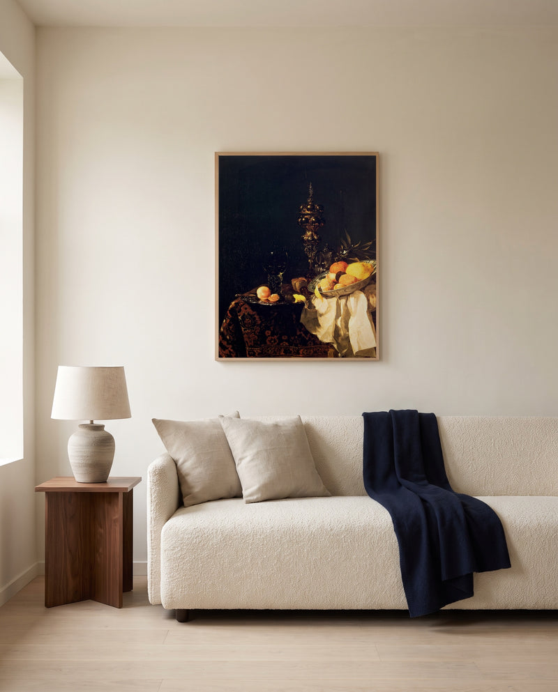 Dessert by Willem Kalf framed in natural oak above a cream sofa in a warm living room